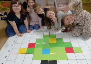 Na macie do kodowania dzieci ułożyły z kolorowych kartoników obrazek choinki